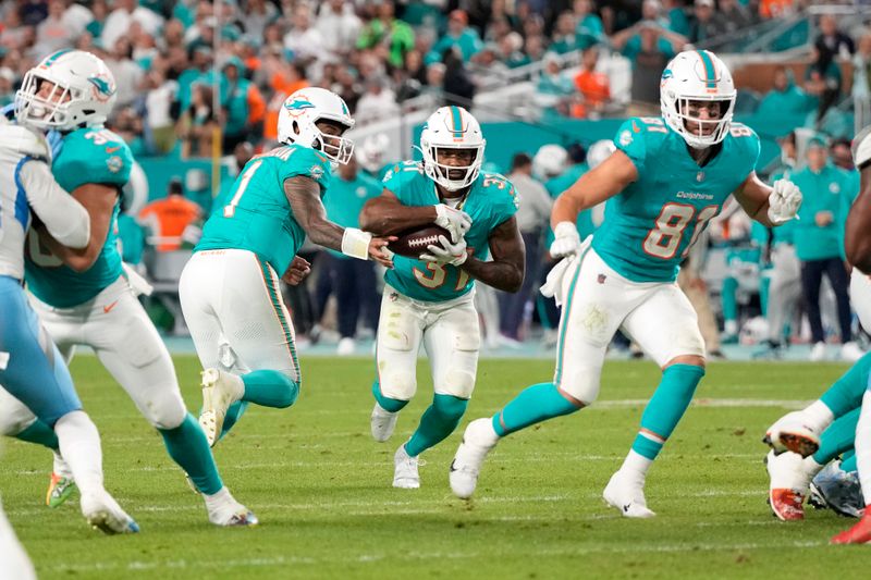 Miami Dolphins quarterback Tua Tagovailoa (1) hands the ball off to running back Raheem Mostert (31) against the Tennessee Titans during an NFL football game, Monday, Dec. 11, 2023, in Miami Gardens, Fla. The Titans defeated the Dolphins 28-27. (AP Photo/Doug Benc)