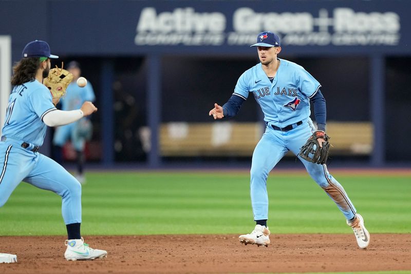 May 30, 2023; Toronto, Ontario, CAN; Toronto Blue Jays second baseman Cavan Biggio (8) tosses the ball to  shortstop Bo Bichette (11) to start a double play during the ninth inning at Rogers Centre. Mandatory Credit: John E. Sokolowski-USA TODAY Sports