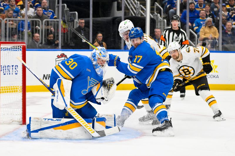 Dec 9, 2025; St. Louis, Missouri, USA; St. Louis Blues goaltender Joel Hofer (30) and defenseman Cam Fowler (17) defend the net against Boston Bruins center Casey Mittelstadt (11) during the first period at Enterprise Center. Mandatory Credit: Jeff Curry-Imagn Images