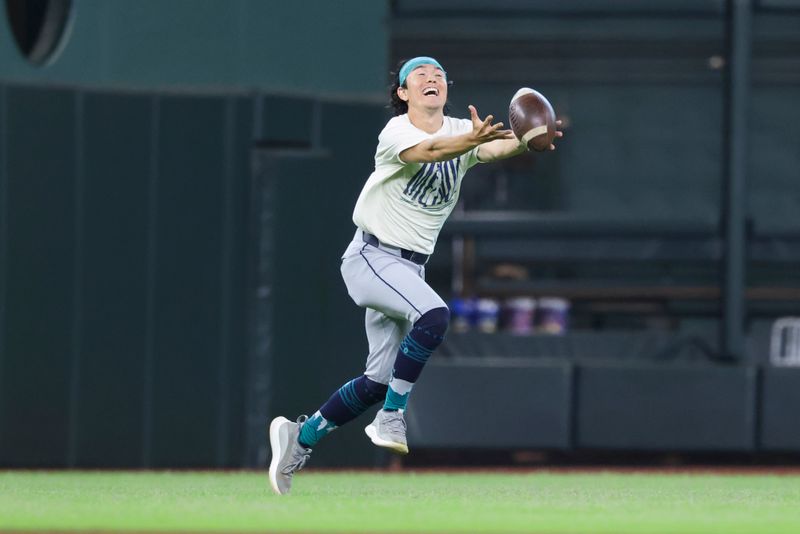 May 25, 2025; Houston, Texas, USA; Seattle Mariners starting pitcher Bryan Woo (22) attempts to catch a thrown football on the field before the game against the Houston Astros at Daikin Park. Mandatory Credit: Troy Taormina-Imagn Images