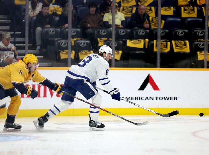Mar 22, 2025; Nashville, Tennessee, USA; Toronto Maple Leafs defenseman Chris Tanev (8) moves the puck past Nashville Predators left wing Filip Forsberg (9) during the first period of the game at Bridgestone Arena. Mandatory Credit: Alan Poizner-Imagn Images