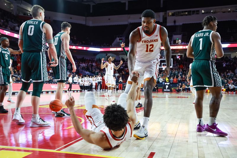 Feb 1, 2025; Los Angeles, California, USA;  USC Trojans forward Rashaun Agee (12) helps  guard Desmond Claude (1) up from the floor against the Michigan State Spartans during the first half at Galen Center. Mandatory Credit: William Navarro-Imagn Images