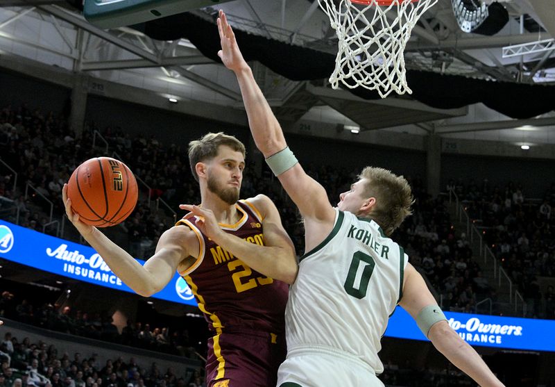 Jan 28, 2025; East Lansing, Michigan, USA;  Minnesota Golden Gophers forward Parker Fox (23) passes around Michigan State Spartans forward Jaxon Kohler (0) during the first half at Jack Breslin Student Events Center. Mandatory Credit: Dale Young-Imagn Images