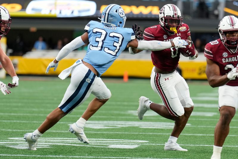 Dec 30, 2021; Charlotte, NC, USA; South Carolina Gamecocks tight end Jaheim Bell (0) tries to elude North Carolina Tar Heels linebacker Cedric Gray (33) during the first quarter at Bank of America Stadium. Mandatory Credit: Jim Dedmon-USA TODAY Sports