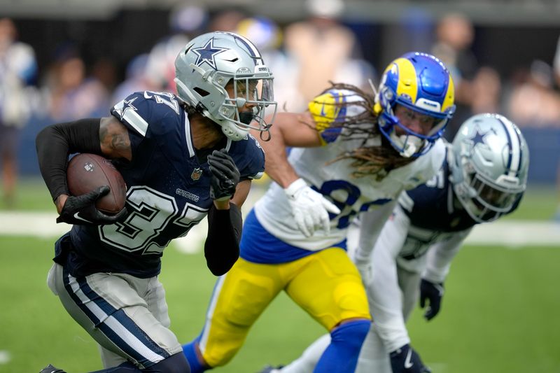 Dallas Cowboys cornerback Eric Scott Jr. (37) returns an interception as Los Angeles Rams wide receiver Jordan Whittington, center, gives chase during the first half of a preseason NFL football game, Sunday, Aug. 11, 2024, in Inglewood, Calif. (AP Photo/Ryan Sun)