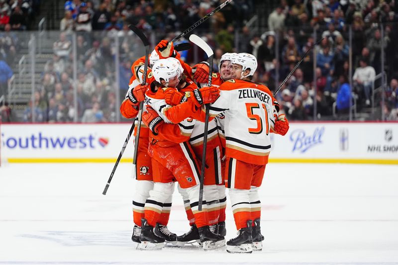 Oct 18, 2024; Denver, Colorado, USA; Anaheim Ducks right wing Troy Terry (19) (center) and center Trevor Zegras (11) and defenseman Olen Zellweger (51) celebrate a game tying goal in the third period against the Colorado Avalanche at Ball Arena. Mandatory Credit: Ron Chenoy-Imagn Images