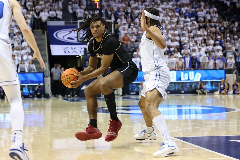 Feb 13, 2024; Provo, Utah, USA; Central Florida Knights guard DeMarr Langford Jr. (12) goes to the basket against Brigham Young Cougars guard Trey Stewart (1) during the first half at Marriott Center. Mandatory Credit: Rob Gray-USA TODAY Sports