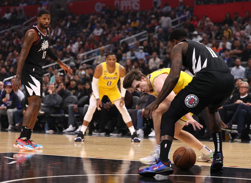 LOS ANGELES, CALIFORNIA - NOVEMBER 09: Austin Reaves #15 of the Los Angeles Lakers loses control of the ball in front of John Wall #11 and Paul George #13 of the LA Clippers during the first quarter at Crypto.com Arena on November 09, 2022 in Los Angeles, California. NOTE TO USER: User expressly acknowledges and agrees that, by downloading and or using this Photograph, User is consenting to the terms and conditions of the Getty Images License Agreement. Mandatory Copyright Notice: Copyright 2022 NBAE. (Photo by Harry How/Getty Images)