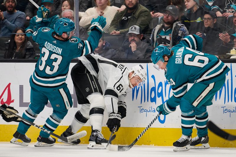 Apr 4, 2024; San Jose, California, USA; Los Angeles Kings center Trevor Lewis (61) plays the puck against San Jose Sharks defenseman Calen Addison (33) and center Mikael Granlund (64) during the third period at SAP Center at San Jose. Mandatory Credit: Robert Edwards-USA TODAY Sports