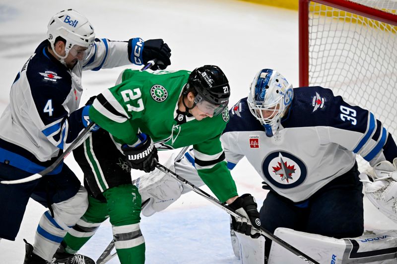 Apr 11, 2024; Dallas, Texas, USA; Winnipeg Jets defenseman Neal Pionk (4) and goaltender Laurent Brossoit (39) and Dallas Stars left wing Mason Marchment (27) battle for control of the puck during the second period at the American Airlines Center. Mandatory Credit: Jerome Miron-USA TODAY Sports