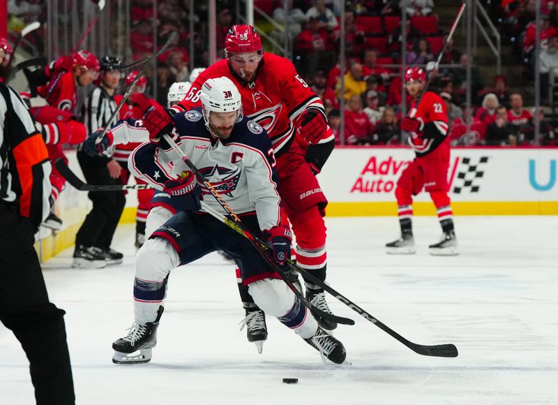 Nov 26, 2023; Raleigh, North Carolina, USA; Columbus Blue Jackets center Boone Jenner (38) and Carolina Hurricanes left wing Michael Bunting (58) battle over the puck during the third period at PNC Arena. Mandatory Credit: James Guillory-USA TODAY Sports