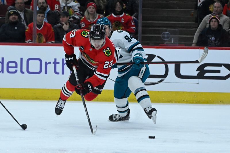 Jan 16, 2024; Chicago, Illinois, USA; Chicago Blackhawks center Philipp Kurashev (23) gets tripped by San Jose Sharks left wing Alexander Barabanov (94) during the first period at United Center. Mandatory Credit: Matt Marton-USA TODAY Sports