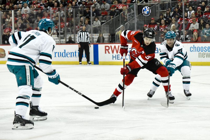 Nov 10, 2024; Newark, New Jersey, USA; New Jersey Devils center Jack Hughes (86) skates with the puck against San Jose Sharks center Luke Kunin (11) and San Jose Sharks left wing William Eklund (72) during the second period at Prudential Center. Mandatory Credit: John Jones-Imagn Images