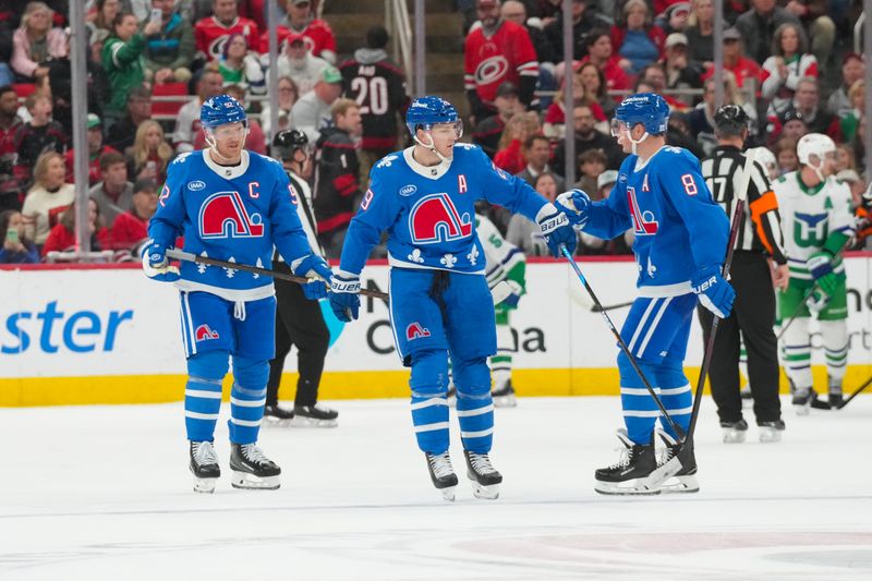 Jan 3, 2026; Raleigh, North Carolina, USA; Colorado Avalanche center Nathan MacKinnon (29) celebrates after scoring an empty net goal with defenseman Cale Makar (8) and left wing Gabriel Landeskog (92) against the Carolina Hurricanes during the third period at Lenovo Center. Mandatory Credit: James Guillory-Imagn Images