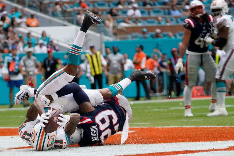 Miami Dolphins wide receiver Cedrick Wilson Jr. (11) scores a touchdown as New England Patriots cornerback J.C. Jackson (29) defends during the first half of an NFL football game, Sunday, Oct. 29, 2023, in Miami Gardens, Fla. (AP Photo/Lynne Sladky)