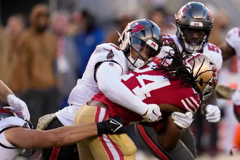 Tampa Bay Buccaneers linebacker SirVocea Dennis, left, tackles San Francisco 49ers running back Jordan Mason (24) during the second half of an NFL football game Sunday, Nov. 19, 2023, in Santa Clara, Calif. (AP Photo/Godofredo A. Vásquez)