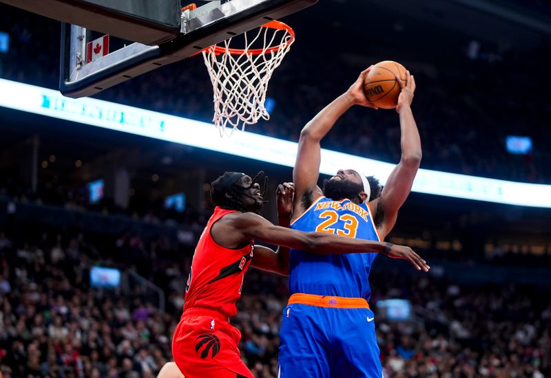 TORONTO, ON - MARCH 27: Mitchell Robinson #23 of the New York Knicks goes to the basket against Mouhamadou Gueye #16 of the Toronto Raptors during the first half of their basketball game at the Scotiabank Arena on March 27, 2024 in Toronto, Ontario, Canada. NOTE TO USER: User expressly acknowledges and agrees that, by downloading and/or using this Photograph, user is consenting to the terms and conditions of the Getty Images License Agreement. (Photo by Mark Blinch/Getty Images)