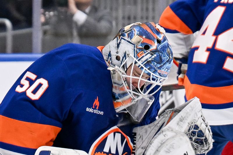 Mar 22, 2025; Elmont, New York, USA; New York Islanders goaltender Marcus Hogberg (50) makes a save against the Calgary Flames during the first period at UBS Arena. Mandatory Credit: Dennis Schneidler-Imagn Images