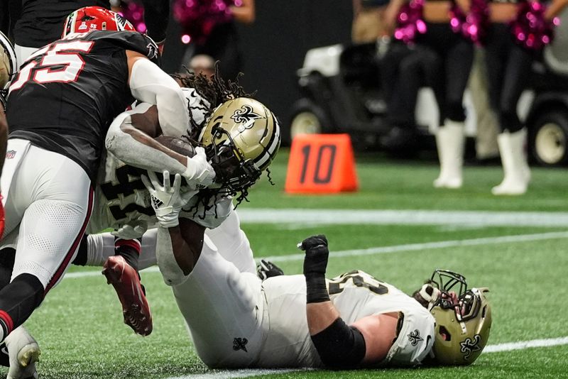 New Orleans Saints running back Alvin Kamara (41) scores a touchdown against Atlanta Falcons linebacker Kaden Elliss (55) during the second half of an NFL football game, Sunday, Sept. 29, 2024, in Atlanta. (AP Photo/John Bazemore)