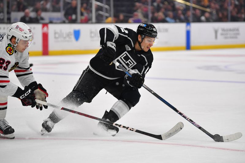 Apr 18, 2024; Los Angeles, California, USA; Los Angeles Kings left wing Trevor Moore (12) moves the puck ahead of Chicago Blackhawks center Philipp Kurashev (23) during the first period at Crypto.com Arena. Mandatory Credit: Gary A. Vasquez-USA TODAY Sports