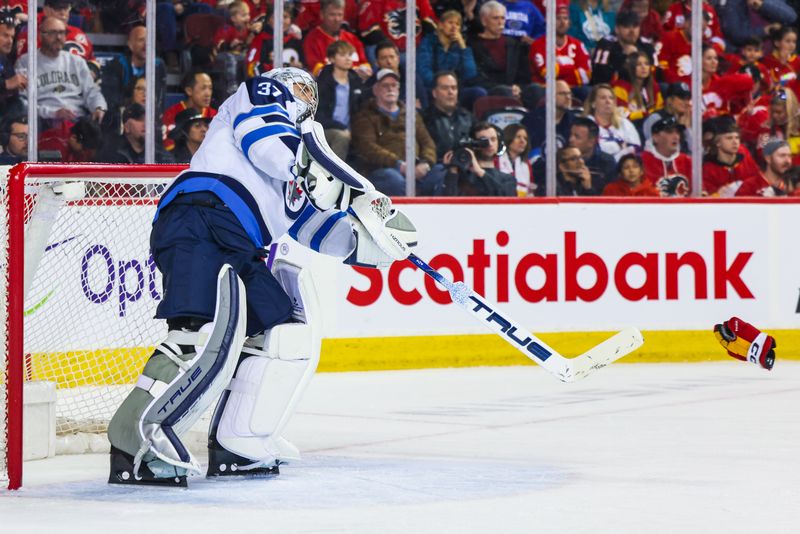 Feb 19, 2024; Calgary, Alberta, CAN; Winnipeg Jets goaltender Connor Hellebuyck (37) passes a Calgary Flames glove during the second period at Scotiabank Saddledome. Mandatory Credit: Sergei Belski-USA TODAY Sports