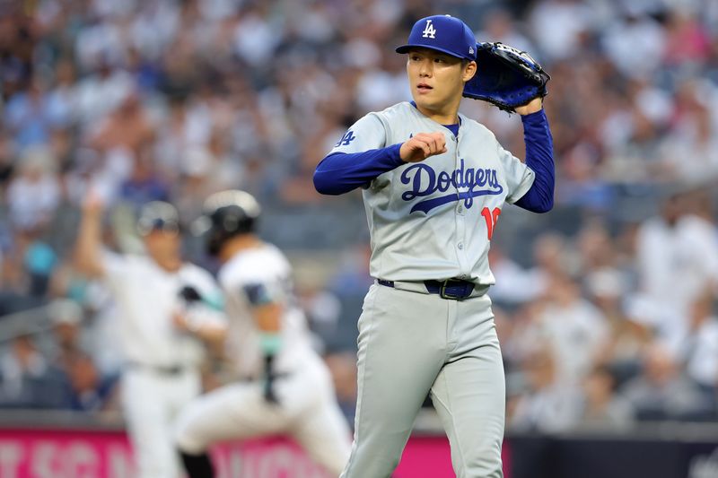 Jun 7, 2024; Bronx, New York, USA; Los Angeles Dodgers starting pitcher Yoshinobu Yamamoto (18) reacts after giving up a double to New York Yankees right fielder Aaron Judge (99) during the first inning at Yankee Stadium. Mandatory Credit: Brad Penner-USA TODAY Sports