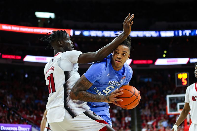 Feb 19, 2023; Raleigh, North Carolina, USA;  North Carolina Tar Heels forward Armando Bacot (5) drives against North Carolina State Wolfpack forward Ebenezer Dowuona (21) during the second half of the game at PNC Arena. Mandatory Credit: Jaylynn Nash-USA TODAY Sports