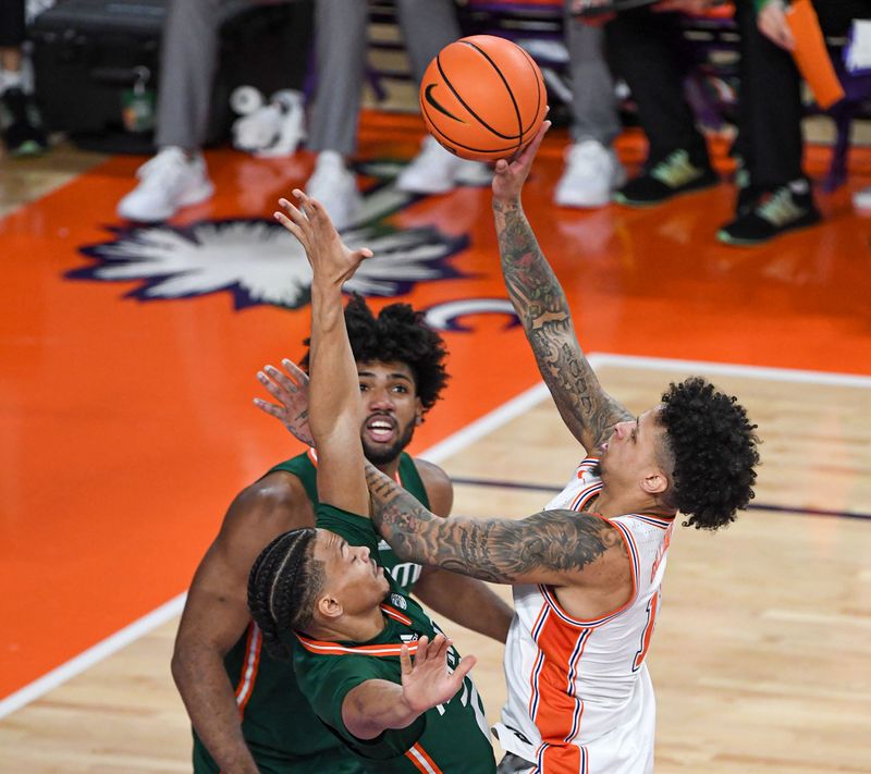 Feb 4, 2023; Clemson, South Carolina, USA; Clemson guard Brevin Galloway (11) shoots near Miami guard Isaiah Wong (2) during the first half at Littlejohn Coliseum in Clemson, S.C. Saturday, Feb. 4, 2023.  Mandatory Credit: Ken Ruinard-USA TODAY Sports