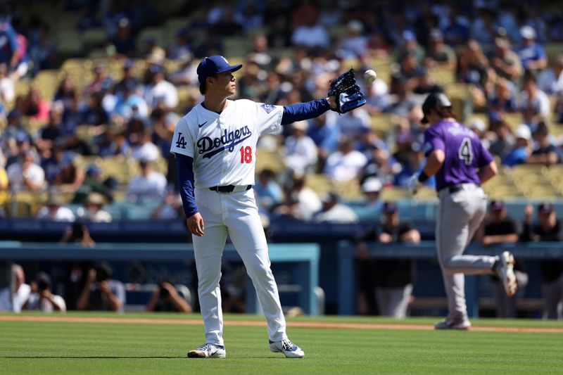 Sep 22, 2024; Los Angeles, California, USA;  Los Angeles Dodgers starting pitcher Yoshinobu Yamamoto (18) catches a ball after walks Colorado Rockies first baseman Michael Toglia (4) during the first inning at Dodger Stadium. Mandatory Credit: Kiyoshi Mio-Imagn Images