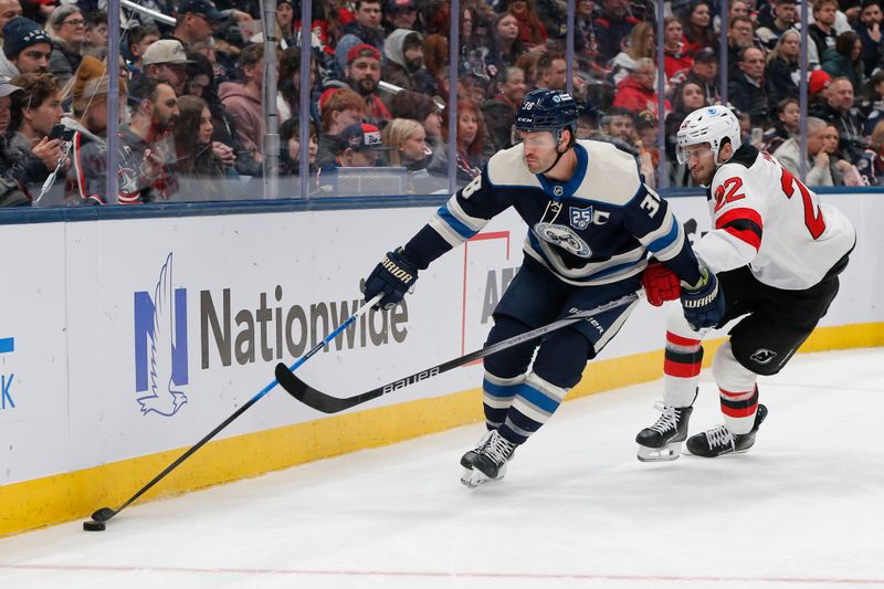 Dec 31, 2025; Columbus, Ohio, USA; Columbus Blue Jackets center Boone Jenner (38) controls the puck as New Jersey Devils defenseman Brett Pesce (22) trails the play during the second period at Nationwide Arena. Mandatory Credit: Russell LaBounty-Imagn Images