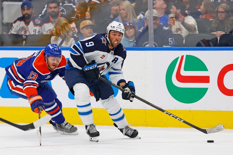 Sep 26, 2025; Edmonton, Alberta, CAN; Winnipeg Jets forward Alex Iafallo (9) gets a shot away in front of Edmonton Oilers forward Mattias Janmark (13) during the second period at Rogers Place. Mandatory Credit: Perry Nelson-Imagn Images