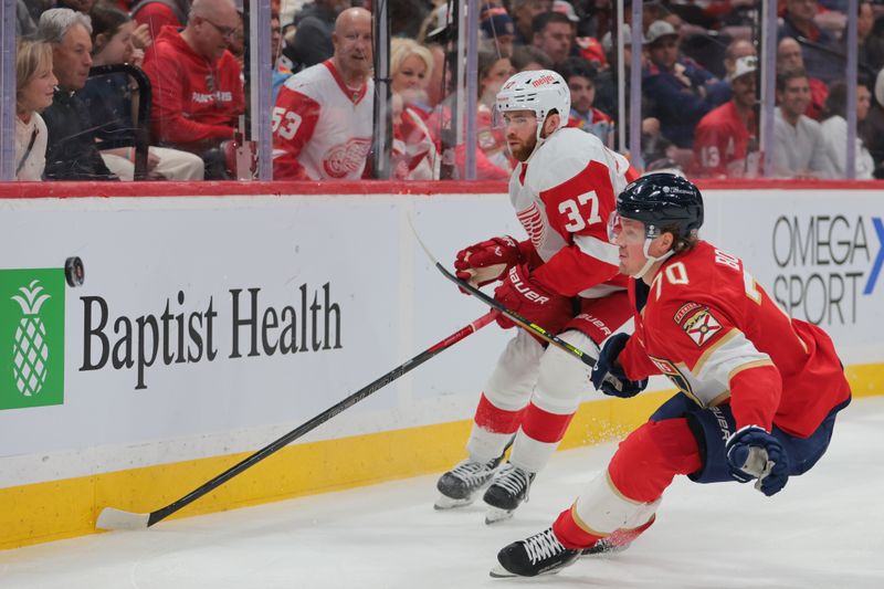 Jan 16, 2025; Sunrise, Florida, USA; Detroit Red Wings left wing J.T. Compher (37) and Florida Panthers center Jesper Boqvist (70) battle for the puck during the first period at Amerant Bank Arena. Mandatory Credit: Sam Navarro-Imagn Images
