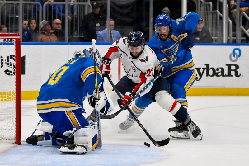 Nov 9, 2024; St. Louis, Missouri, USA;  Washington Capitals defenseman Alexander Alexeyev (27) shoots as St. Louis Blues goaltender Jordan Binnington (50) and defenseman Justin Faulk (72) defend the net during the first period at Enterprise Center. Mandatory Credit: Jeff Curry-Imagn Images