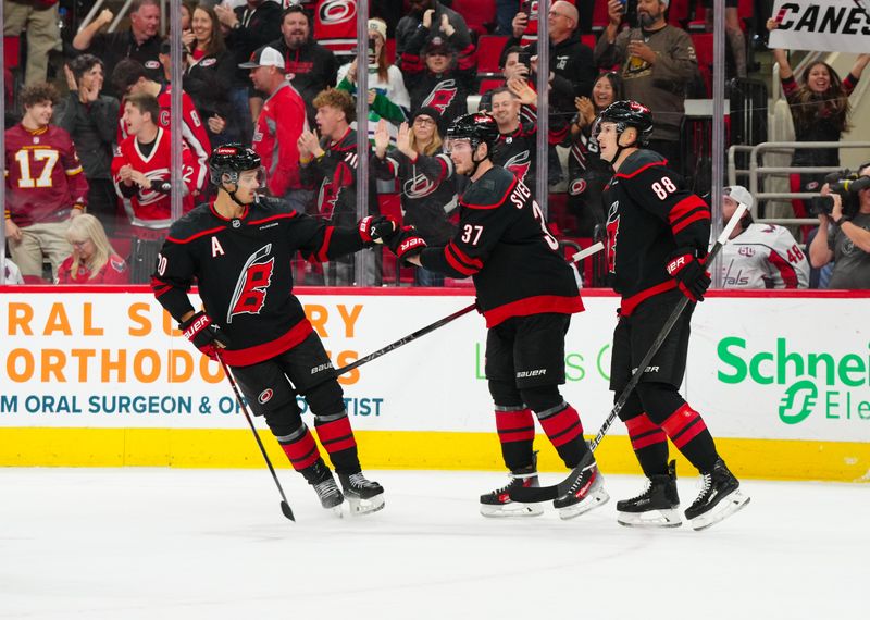 Nov 3, 2024; Raleigh, North Carolina, USA;  Carolina Hurricanes right wing Andrei Svechnikov (37) is congratulated by center Martin Necas (88) and center Sebastian Aho (20) after his empty net goal against the Washington Capitals during the third period at Lenovo Center. Mandatory Credit: James Guillory-Imagn Images