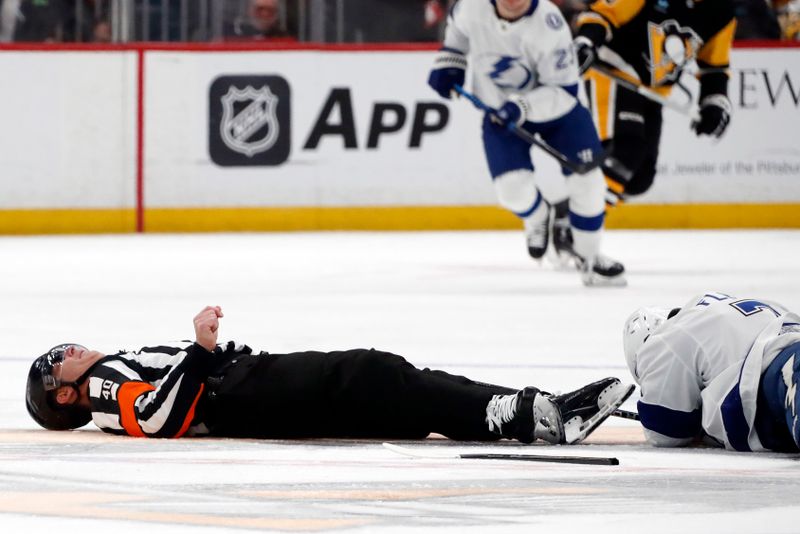 Apr 6, 2024; Pittsburgh, Pennsylvania, USA;  NHL referee Steve Kozari (40) lays on the ice after an accidental collision with Tampa Bay Lightning defenseman Haydn Fleury (7) during the third period of the game against the Pittsburgh Penguins at PPG Paints Arena. The Penguins won 5-4. Mandatory Credit: Charles LeClaire-USA TODAY Sports