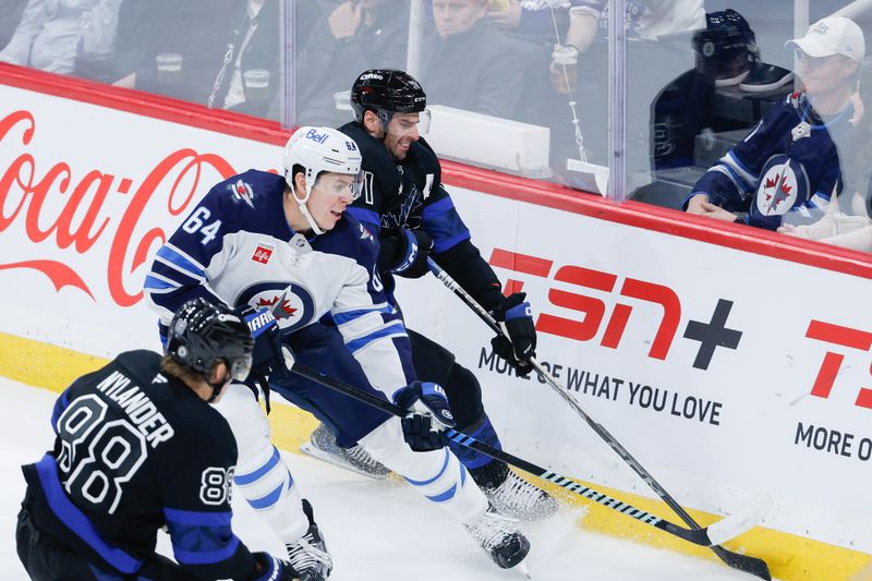 Oct 28, 2024; Winnipeg, Manitoba, CAN;  Toronto Maple Leafs forward John Taveres (91) battles Winnipeg Jets defenseman Logan Stanley (64) for the puck during the second period at Canada Life Centre. Mandatory Credit: Terrence Lee-Imagn Images