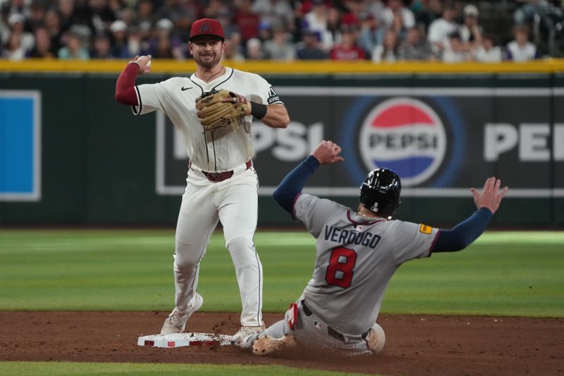 Apr 27, 2025; Phoenix, Arizona, USA; Arizona Diamondbacks second base Tim Tawa (13) turns the double play while avoiding Atlanta Braves outfielder Alex Verdugo (8) in the ninth inning at Chase Field. Mandatory Credit: Rick Scuteri-Imagn Images