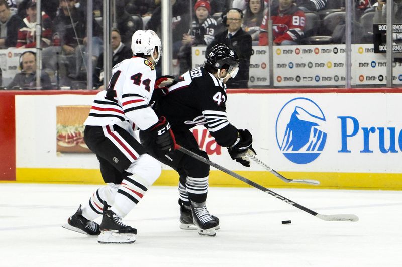 Dec 14, 2024; Newark, New Jersey, USA; New Jersey Devils center Paul Cotter (47) skates with the puck while being defended by Chicago Blackhawks defenseman Wyatt Kaiser (44) during the second period at Prudential Center. Mandatory Credit: John Jones-Imagn Images