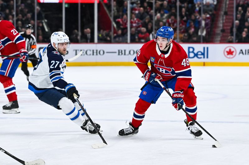 Jan 28, 2025; Montreal, Quebec, CAN; Montreal Canadiens defenseman Lane Hutson (48) plays the puck against Winnipeg Jets left wing Nikolaj Ehlers (27) during the second period at Bell Centre. Mandatory Credit: David Kirouac-Imagn Images