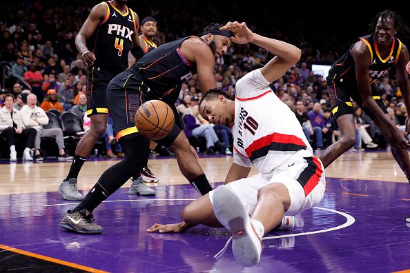 PHOENIX, ARIZONA - JANUARY 01: Josh Okogie #2 of the Phoenix Suns and Moses Brown #10 of the Portland Trail Blazers battle for a loose ball during the first half at Footprint Center on January 01, 2024 in Phoenix, Arizona. NOTE TO USER: User expressly acknowledges and agrees that, by downloading and or using this photograph, User is consenting to the terms and conditions of the Getty Images License Agreement.  (Photo by Chris Coduto/Getty Images)