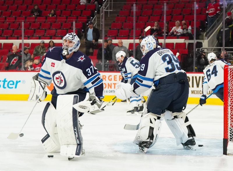 Mar 2, 2024; Raleigh, North Carolina, USA; Winnipeg Jets goaltender Connor Hellebuyck (37) and goaltender Laurent Brossoit (39) change out spot in the net for the warmups before the game against the Carolina Hurricanes at PNC Arena. Mandatory Credit: James Guillory-USA TODAY Sports