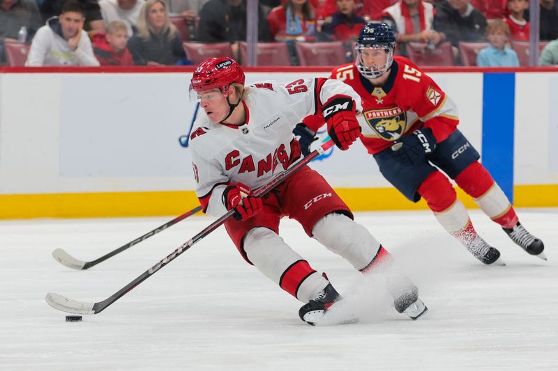 Nov 30, 2024; Sunrise, Florida, USA; Carolina Hurricanes right wing Jackson Blake (53) moves the puck past Florida Panthers center Anton Lundell (15) during the first period at Amerant Bank Arena. Mandatory Credit: Sam Navarro-Imagn Images