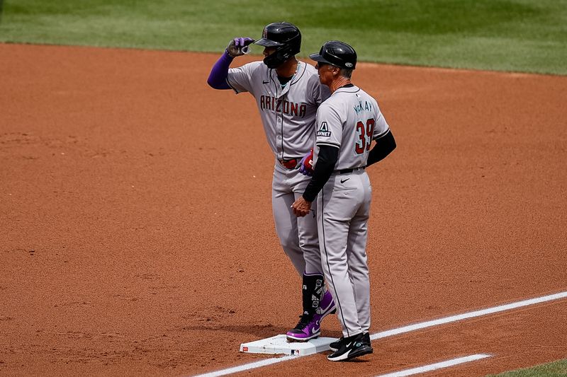 Apr 10, 2024; Denver, Colorado, USA; Arizona Diamondbacks left fielder Lourdes Gurriel Jr. (12) gestures from first next to coach Dave McKay (39) after hitting an RBI single in the first inning against the Colorado Rockies at Coors Field. Mandatory Credit: Isaiah J. Downing-USA TODAY Sports