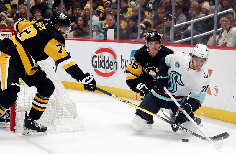 Jan 15, 2024; Pittsburgh, Pennsylvania, USA; Seattle Kraken center Alex Wennberg (21) moves the puck from his knees as Pittsburgh Penguins defenseman Pierre-Olivier Joseph (73) and center Noel Acciari (55) defend during the second period at PPG Paints Arena. Mandatory Credit: Charles LeClaire-USA TODAY Sports