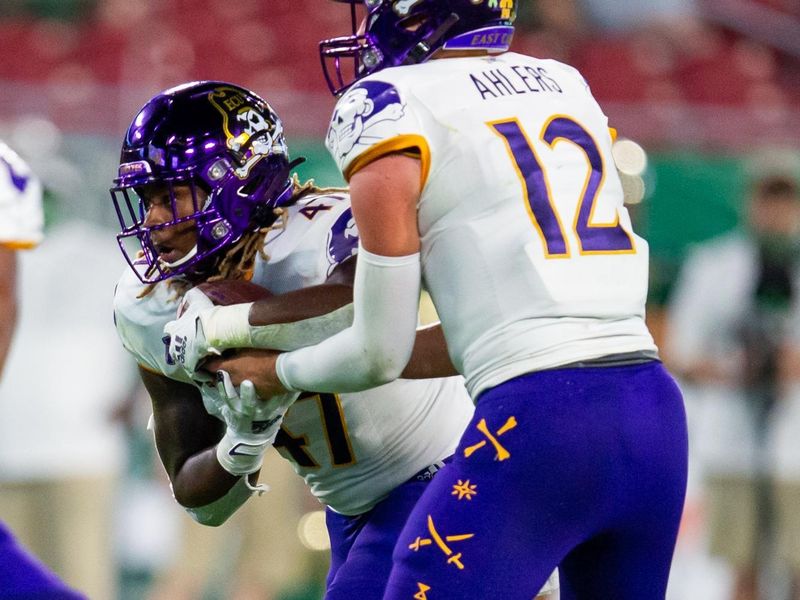 Oct 10, 2020; Tampa, Florida, USA; East Carolina Pirates quarterback Holton Ahlers (12) hands off the ball to running back Rahjai Harris (47) during the first quarter of a game against the South Florida Bulls at Raymond James Stadium. Mandatory Credit: Mary Holt-USA TODAY Sports