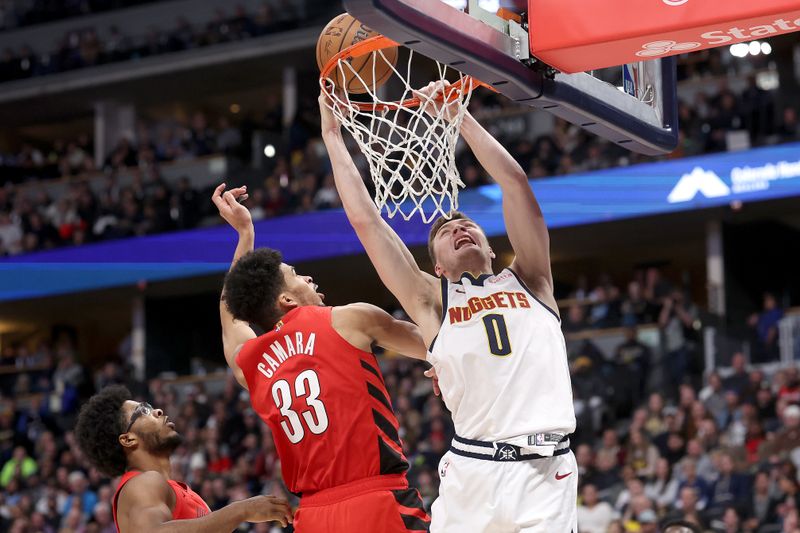 DENVER, COLORADO - FEBRUARY 04: Christian Braun #0 of the Denver Nuggets is fouled going to the basket by Toumani Camara #33 of the Portland Trail Blazers in the third quarter at Ball Arena on February 04, 2024 in Denver, Colorado.  NOTE TO USER: User expressly acknowledges and agrees that, by downloading and or using this photograph, User is consenting to the terms and conditions of the Getty Images License Agreement.  (Photo by Matthew Stockman/Getty Images)