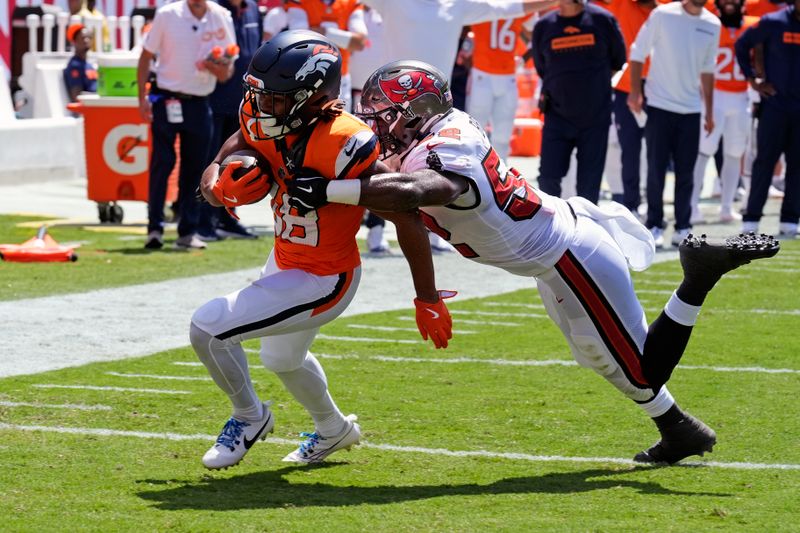 Denver Broncos running back Jaleel McLaughlin, left, gets past Tampa Bay Buccaneers linebacker K.J. Britt for a 1-yard touchdown run during the first half of an NFL football game, in Tampa, Fla. on Sunday, Sept. 22, 2024. (AP Photo/Chris O'Meara)