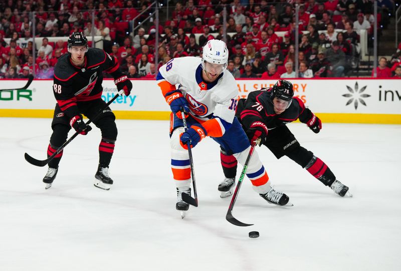 Apr 30, 2024; Raleigh, North Carolina, USA; New York Islanders left wing Pierre Engvall (18) tries to control the puck against Carolina Hurricanes defenseman Brady Skjei (76) during the second period in game five of the first round of the 2024 Stanley Cup Playoffs at PNC Arena. Mandatory Credit: James Guillory-USA TODAY Sports