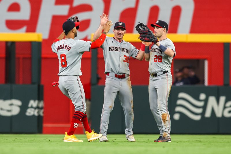 May 30, 2024; Atlanta, Georgia, USA; Washington Nationals left fielder Eddie Rosario (8) and center fielder Jacob Young (30) and right fielder Lane Thomas (28) celebrate after a victory against the Atlanta Braves at Truist Park. Mandatory Credit: Brett Davis-USA TODAY Sports