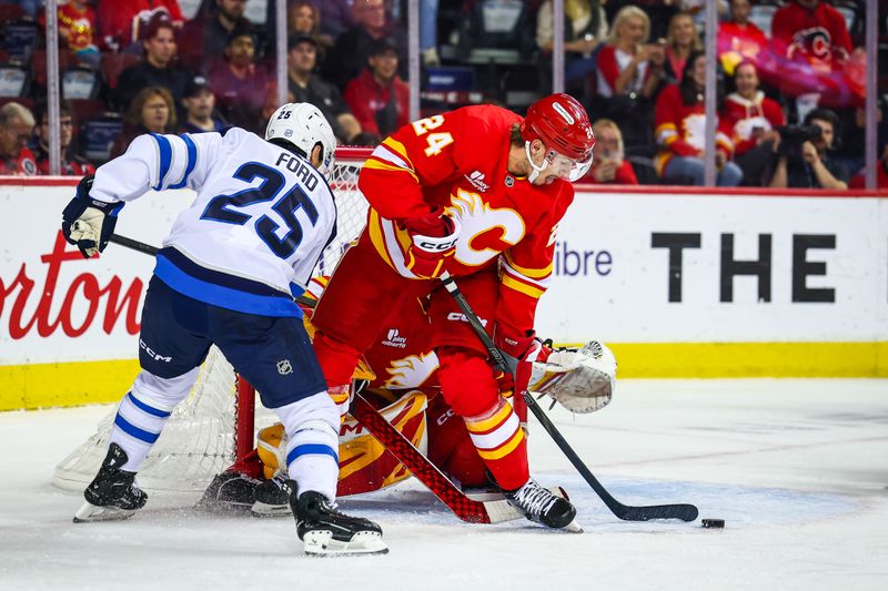 Oct 3, 2025; Calgary, Alberta, CAN; Calgary Flames defenseman Jake Bean (24) and Winnipeg Jets center Parker Ford (25) battles for the puck in front of Calgary Flames goaltender Dustin Wolf (32) during the first period at Scotiabank Saddledome. Mandatory Credit: Sergei Belski-Imagn Images